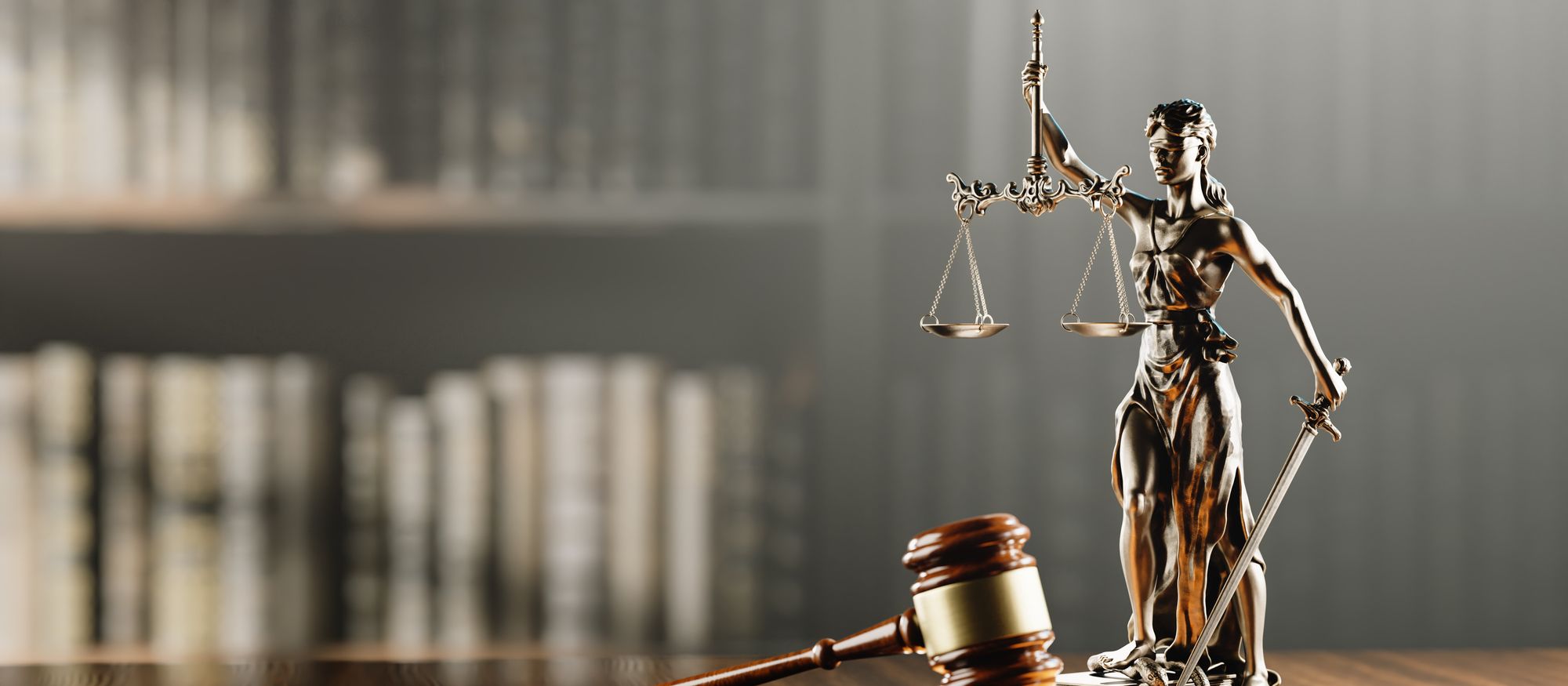 A statue of Lady Justice holding the scales beside a judge's gavel